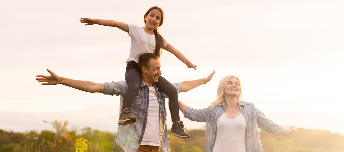 Couple with daughter pretending to fly in a field near Show Low, Arizona.